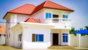 A two-story house with a red roof, white exterior, and a balcony with a white balustrade. - Lawson Guest house  (Kweiman)