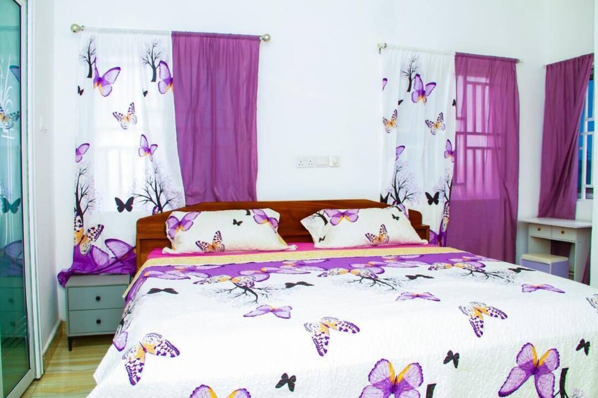 A bedroom with a bed, curtains, a nightstand, and a dresser.