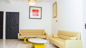 A living room with two sofas, a coffee table, a chandelier, and two doors. - Lawson Guest house  (Kweiman)