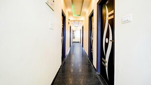 A hotel hallway with a black marble floor, white walls, and doors with a geometric design. - Deluxeganakkal Near BGS Hospital Junction (Bengaluru)