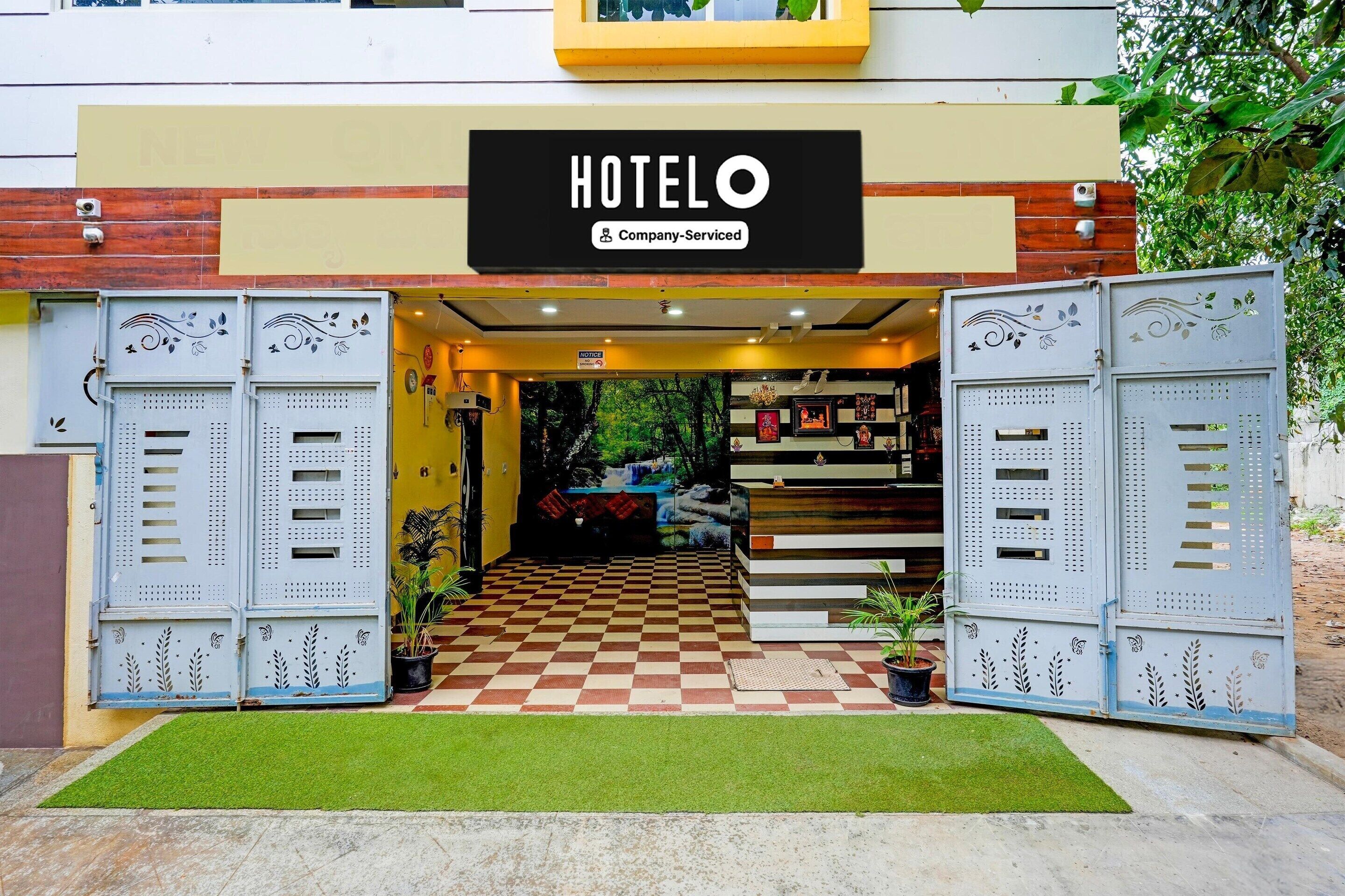 L’entrée d’un hôtel avec un sol à carreaux, des portails en métal et un panneau indiquant qu’il est géré par une entreprise.