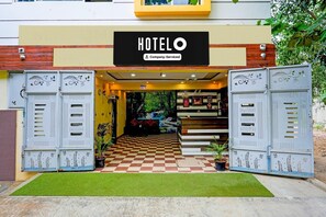 Ein Hotel Eingang mit Schachbrettboden, Metallgittern und einem Schild, das eine betriebsbezogene Betreuung anzeigt.