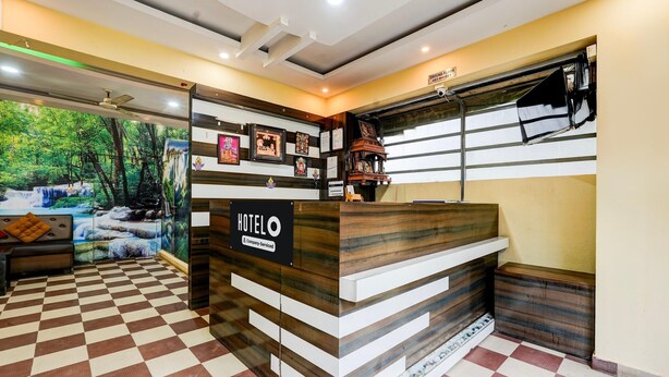 A hotel reception desk with a checkered floor, framed pictures on the wall, and a sign reading 'HOTEL O & Company Serviced.' - Deluxeganakkal Near BGS Hospital Junction (Bengaluru)