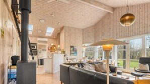 Un intérieur moderne avec un canapé noir, un plancher en bois, une grande fenêtre et un radiateur noir.
