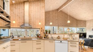 Une cuisine moderne avec des murs en bois, des armoires blanches et des luminaires suspendus.