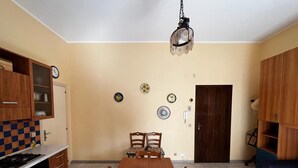 Une cuisine équipée d’une table à manger, de chaises, d’une cuisinière, de placards et d’un luminaire suspendu.