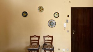 Une pièce avec deux chaises en bois, une porte en bois et des assiettes décoratives accrochées au mur.