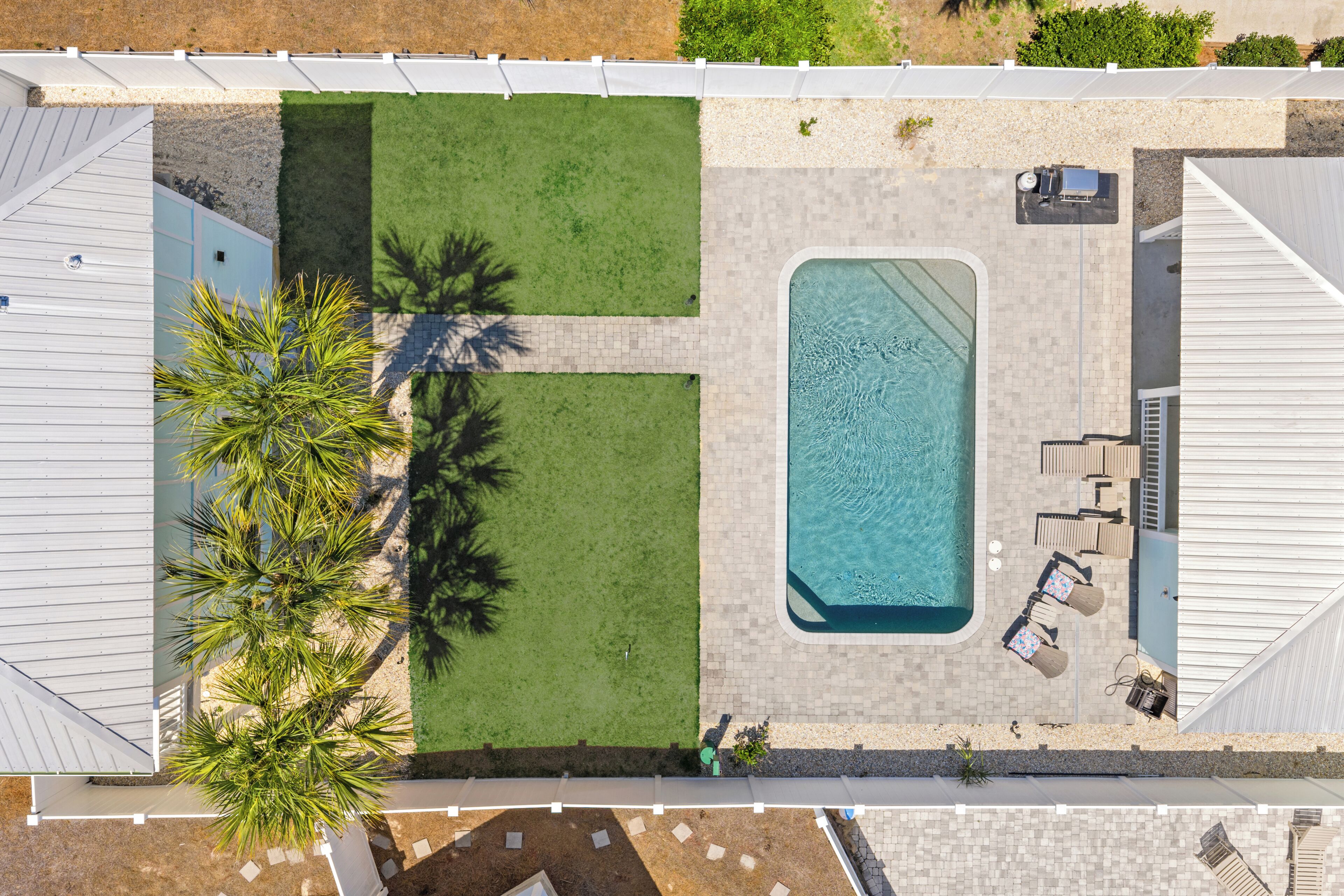 Vue aérienne d’une propriété dotée d’une piscine, d’un espace de détente et d’une pelouse bien entretenue.