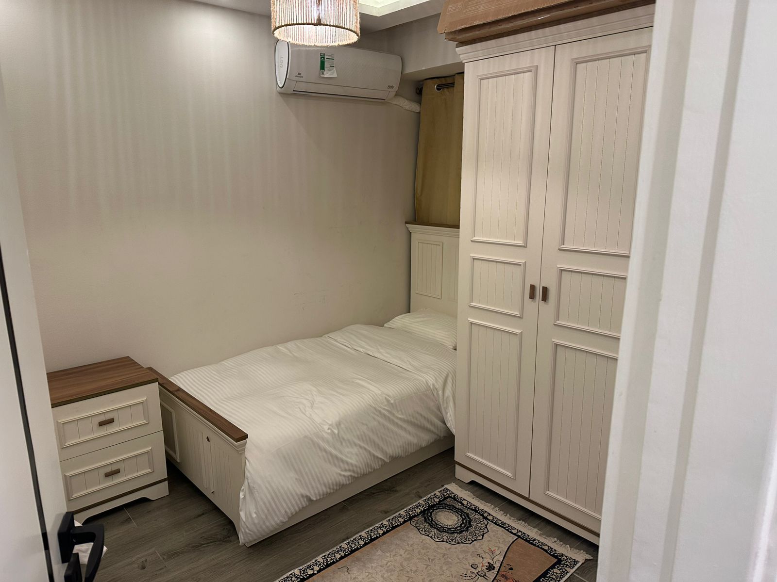 Een slaapkamer met een bed, een kledingkast, een nachtkastje en een airconditioning.