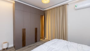Une chambre à coucher avec un lit, une armoire, un miroir et une fenêtre avec des rideaux.