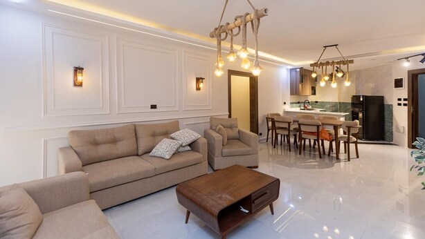 Un salon moderne comprenant un canapé, des fauteuils, une table basse et un coin repas avec des chaises.