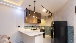 Une cuisine moderne dotée d’un îlot central, d’appareils électroménagers intégrés et de luminaires suspendus.