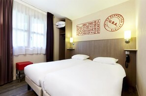 A hotel room with two beds, a red bench, a window with sheer curtains, and a wall with a U.S.A. stamp and text.