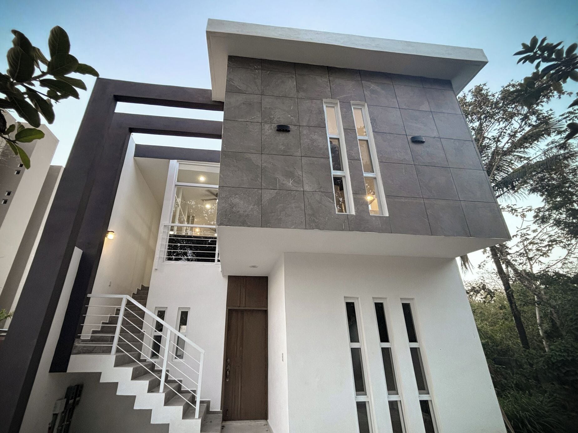 A modern two-story building with a staircase, large windows, and a flat roof.
