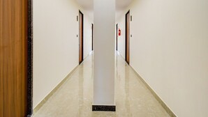 A long, narrow hallway with white walls and a polished floor, leading to multiple doors. - Deluxe Tolkanti Arc (Hyderabad)