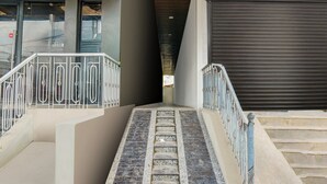 A modern building entrance with a metal railing, a staircase, and a closed garage door. - Deluxe Tolkanti Arc (Hyderabad)