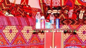 A room with a patterned red carpet, a small table with water bottles, and a decorative border. - Pyramids Essence hotel (Giza)