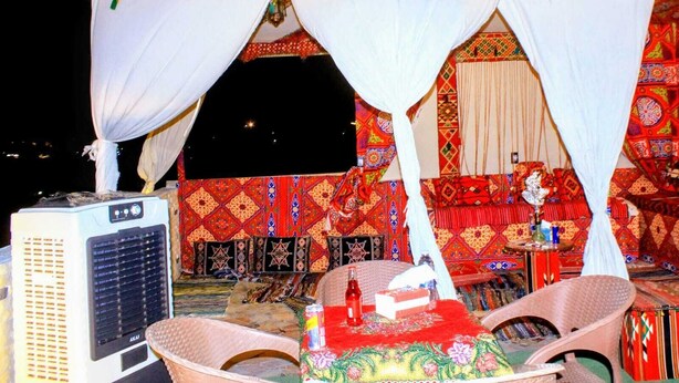 A room with a bed, a heater, and a table with a bottle and tissue box. - Pyramids Essence hotel (Giza)