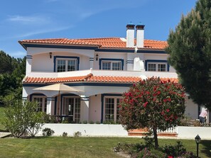 Una casa de dos pisos amb teules vermelles, parets blanques i detalls blaus.
