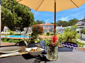 Zona de dinar a l'aire lliure amb una taula preparada per a dues persones, una piscina i vista a una zona residencial.