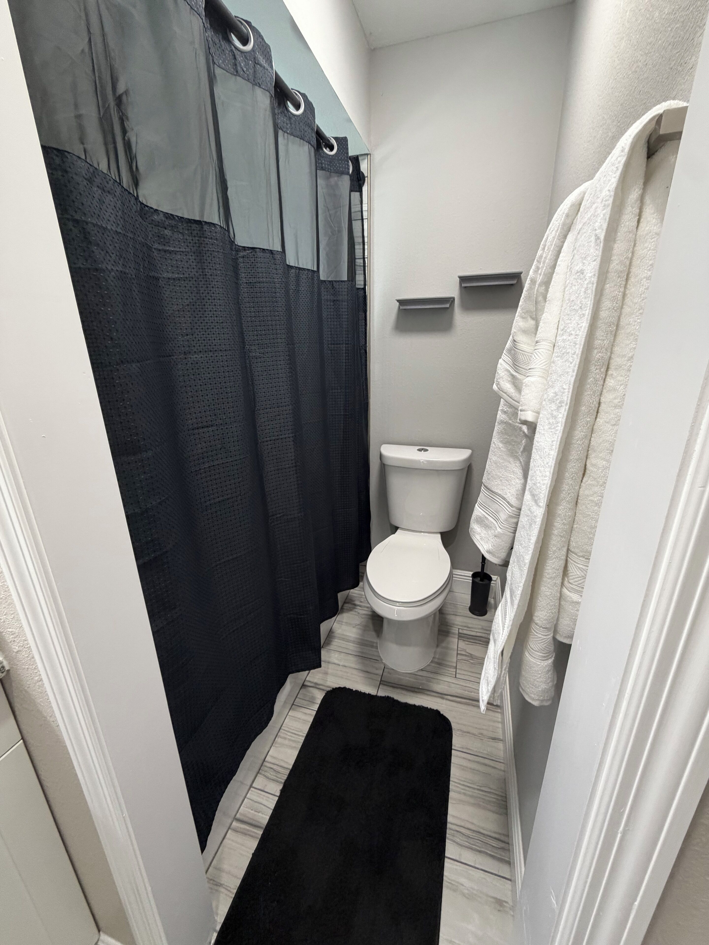 A compact bathroom with a shower curtain, toilet, and towels.