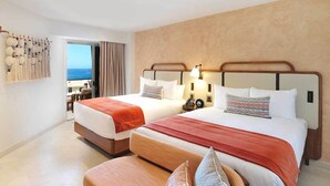 Ein Hotelzimmer mit zwei Betten, einer hölzernen Bank und Blick aufs Meer.