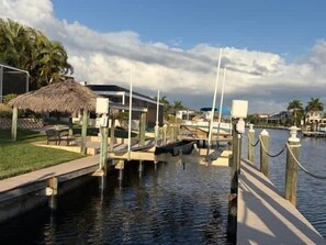 A marina with boats docked, a thatched-roof structure, and a waterway. - Villa Blue Water - Cape Coral (Cape Coral)