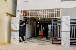 A gated entrance with a checkered floor, a decorative ceiling, and a security camera. - Deluxegn Luxury Suits (Hyderabad)