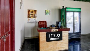 Una recepción con un letrero que dice 'HOTELO Company Serviced', una puerta roja, un refrigerador verde y un cartel en la pared.