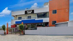 Un hotel de dos pisos con un diseño moderno, que destaca un letrero grande que dice 'HOTEL', una entrada cubierta y un camino de acceso con portones.