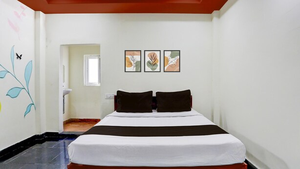 Habitación de hotel con una cama, una puerta, un ventanal y tres cuadros en la pared.
