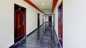 Un pasillo con puertas, piso de baldosas e iluminación empotrada en el techo.