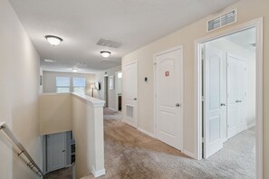 A hallway with carpeted floors, white walls, and doors leading to other rooms. - Magical 6BR Retreat Near Disney | Private Pool & Spa | Themed Rooms (Kissimmee)