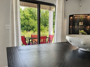 Un comedor con una mesa y sillas, un tazón grande sobre la mesa y vistas a zonas verdes al exterior.