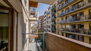 Een woongebouw met meerdere balkons, een houten hekwerk en uitzicht op omliggende gebouwen.