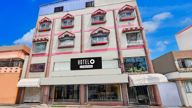 A multi-story hotel with balconies, a sign indicating it is company-serviced, and a clear blue sky in the background. - Deluxe Rupashi Restaurant And Guest House (Shrirampur)