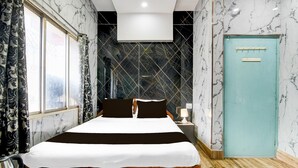 A hotel room with a bed, a nightstand, a lamp, a window with curtains, and a door. - Deluxe Rupashi Restaurant And Guest House (Shrirampur)