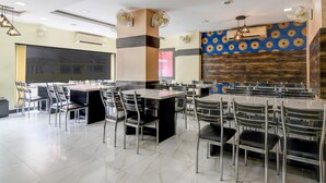A spacious dining area with multiple tables and chairs, ceiling fans, and an air conditioning unit. - Deluxe Rupashi Restaurant And Guest House (Shrirampur)