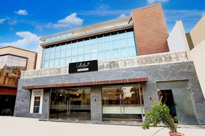 A building with a modern facade, large windows, and a sign indicating a company service. - Suite Hotel Ashoka (Alwar)