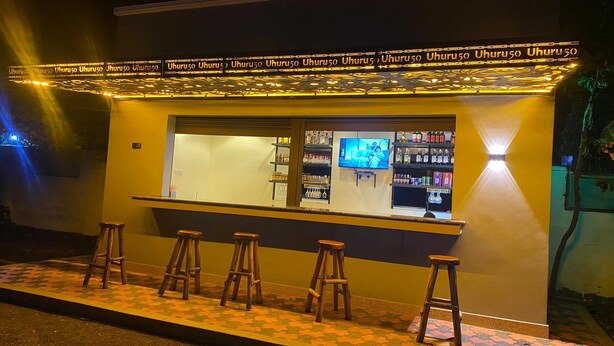 Eine Bar mit Hockstühlen, einer Theke und Regalen voller Flaschen.