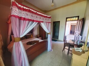 Ein Schlafzimmer mit Baldachinbett, einem Holztisch mit Telefon und einem Spiegel.