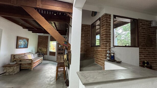 A rustic interior with exposed wooden beams, a brick wall, a stone bench, and a wooden table. - Rustic and cozy beach house with 4 ensuites (Vila Velha)