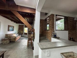 Ein rustikales Interieur mit freiliegenden Holzbalken, einer Ziegelwand, einer Steinsitzbank und einem Holztisch.