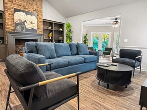 Un salon moderne avec un canapé bleu, un fauteuil noir, une table basse ronde et une cheminée.