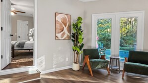 Ein geräumiger Raum mit Holzboden, einem grünen Sessel, einem Topfpflanzen und einem Gemälde an der Wand.