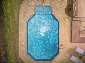 Une piscine octogonale aux parois bleues, entourée d’une terrasse en béton.