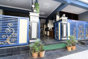 A building entrance with blue decorative gates, potted plants, and a green mat. - Deluxepr Stay Inn (Hyderabad)