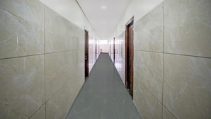 A corridor with marble walls and doors, leading to a bright interior space. - Deluxe Hotel O Sunkadakatte (Bengaluru)
