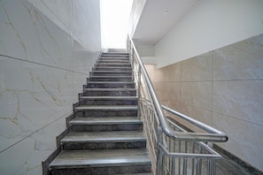 A marble staircase with metal railings, leading upwards in a modern building. - Deluxe Hotel O Sunkadakatte (Bengaluru)