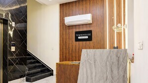 A reception area with a sign reading "TOWNHOUSE," a wooden reception desk, a marble counter, and a staircase with black steps. - Deluxe GT Road Amritsar (Amritsar)